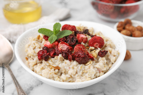 Oatmeal with freeze dried strawberries and mint on white marble table, closeup