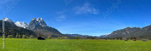 Panoramic view of a lush green meadow with Waxenstein mountain in the background in Grainau