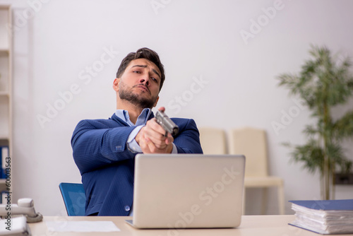 Young male employee holding gun at workplace