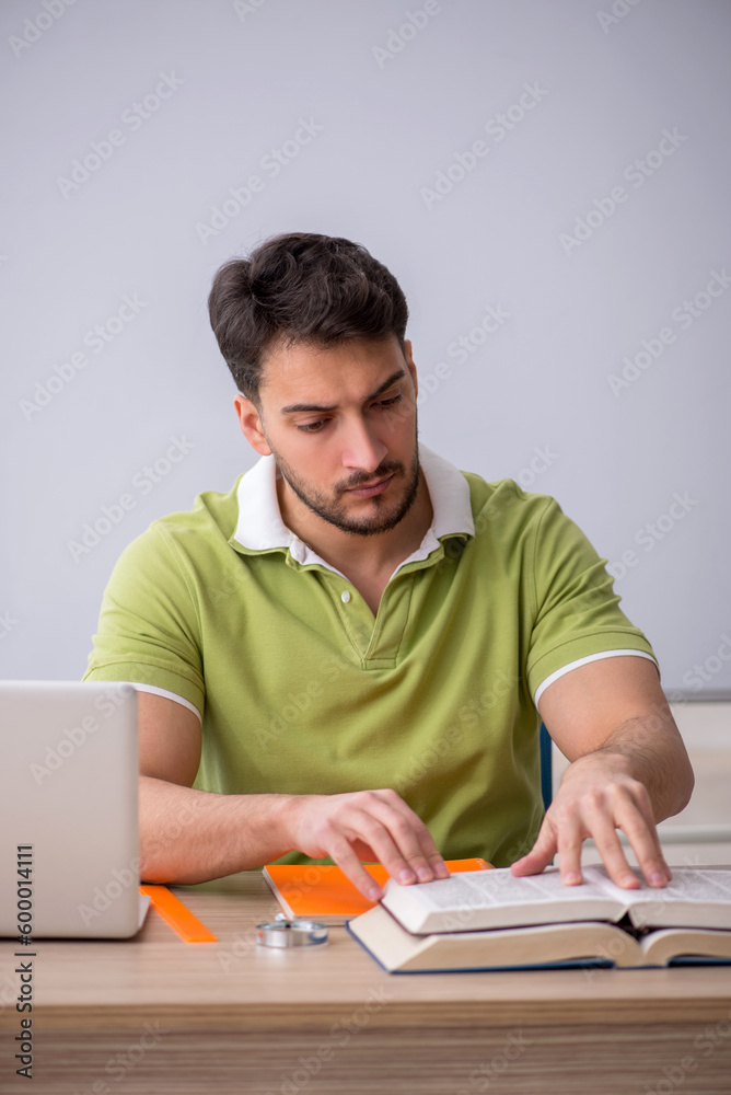 Young male student sitting in front of whiteboard Young male student sitting in front of whiteboard