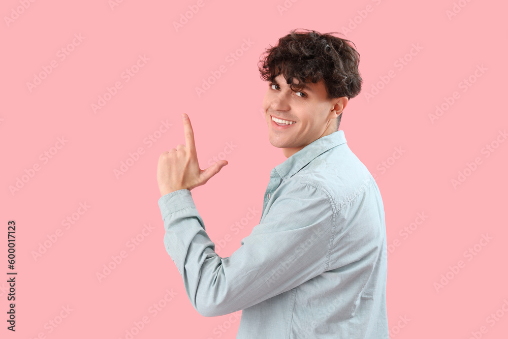 Young man showing loser gesture on pink background Young man showing loser gesture on pink background