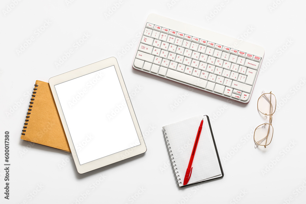 Composition with tablet computer, notebook, keyboard and glasses on white background