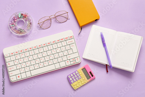 Composition with keyboard, glasses, notebook and stationery on lilac background