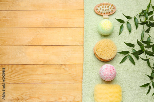 Bath bombs with massage brushes, plant branches and towel on wooden background
