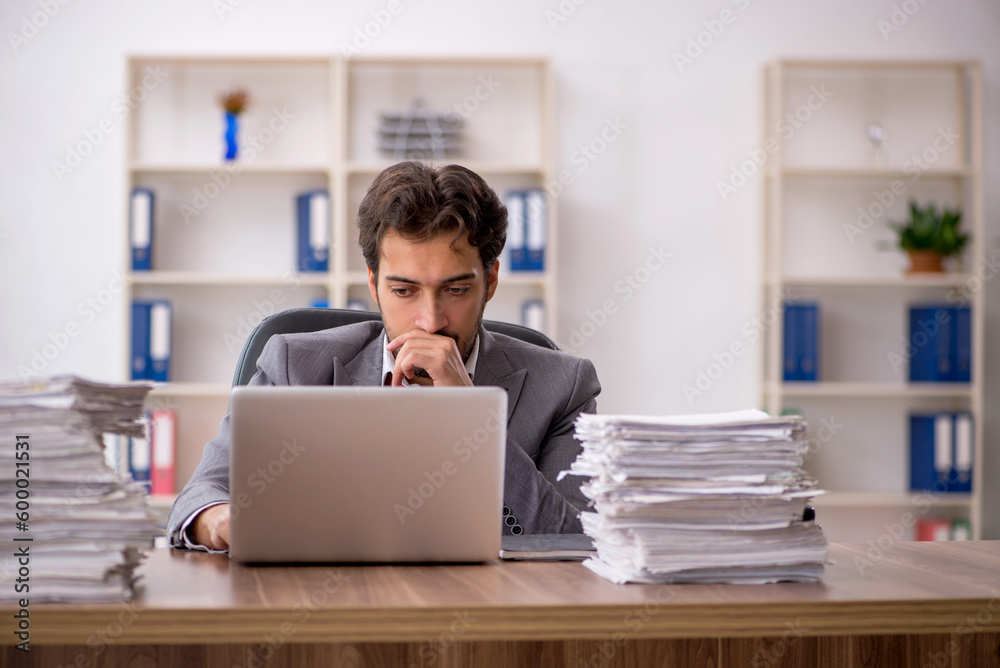 Young male employee unhappy with excessive work in the office Young male employee unhappy with excessive work in the office