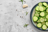 Plate with pieces of fresh cucumber on light background