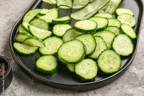 Tray with pieces of fresh cucumber on grunge background, closeup