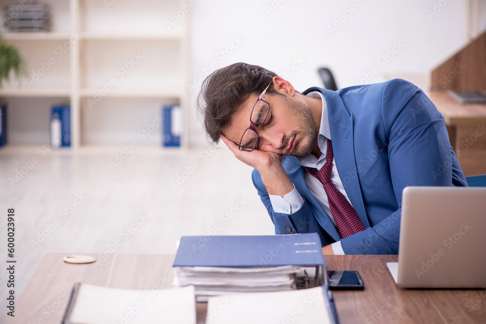 Young male employee unhappy with excessive work in the office Young male employee unhappy with excessive work in the office