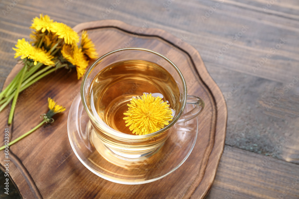 Board with glass cup of healthy dandelion tea on wooden background Board with glass cup of healthy dandelion tea on wooden background