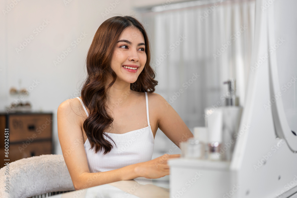 Smiling of beautiful asian woman fresh healthy white skin, clean, looking at mirror.asian girl touching on face applying cream, skincare, cosmetics, cosmetology, beauty, fashion at home.spa, wellness Smiling of beautiful asian woman fresh healthy white skin, clean, looking at mirror.asian girl touching on face applying cream, skincare, cosmetics, cosmetology, beauty, fashion at home.spa, wellness
