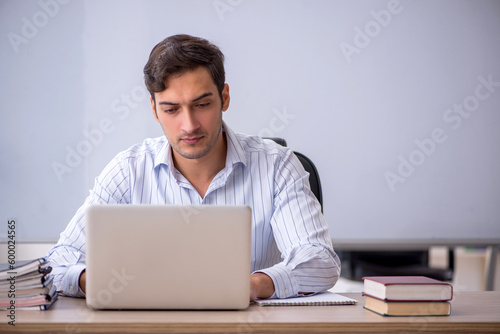 Young male teacher sitting in the classroom