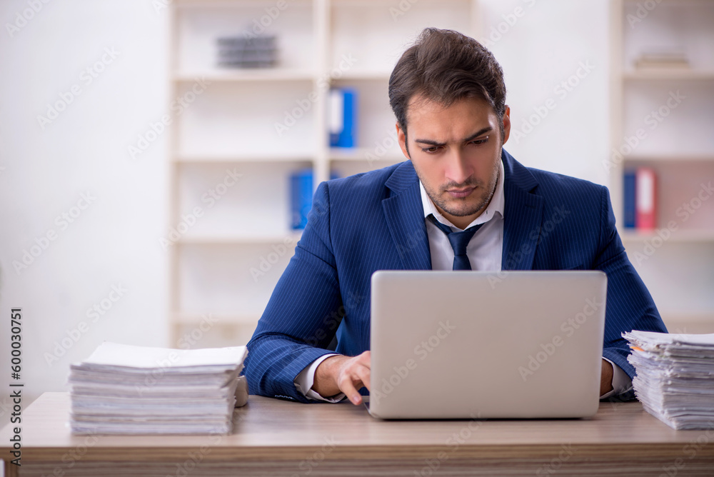 Young male employee and too much work in the office Young male employee and too much work in the office