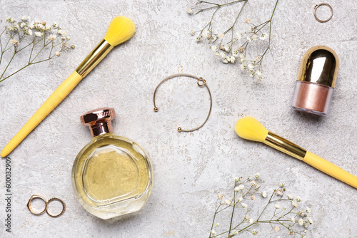 Composition with female accessories, makeup brushes, cosmetics and gypsophila flowers on light background