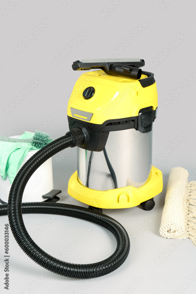 Vacuum cleaner with supplies and carpet on grey background Vacuum cleaner with supplies and carpet on grey background