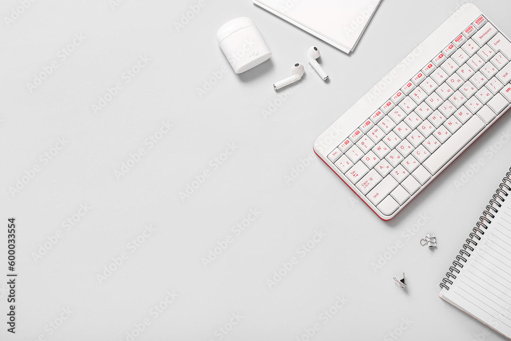 Composition with keyboard, earphones and notebooks on white background Composition with keyboard, earphones and notebooks on white background