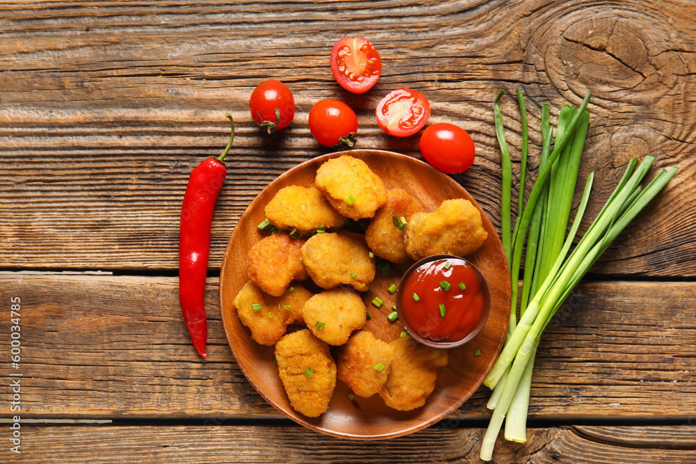 Plate with delicious nuggets, bowl of ketchup and vegetables on wooden table Plate with delicious nuggets, bowl of ketchup and vegetables on wooden table