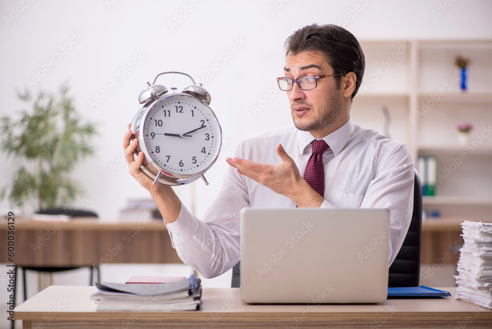 Young male employee in time management concept Young male employee in time management concept