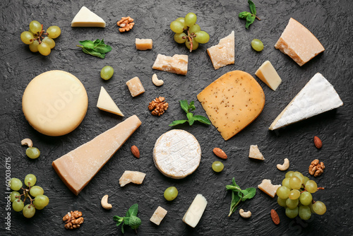Tableau sur toile Different types of tasty cheese, grapes and nuts on dark background