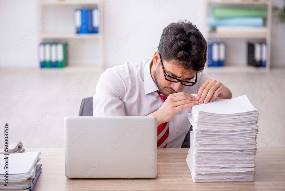 Young male employee and too much work in the office Young male employee and too much work in the office