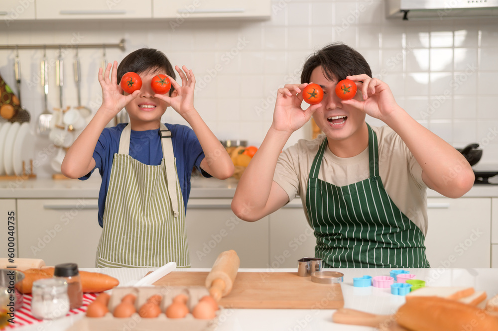 Happy smiling Young Asian father and son holding tomato , enjoy cooking in kitchen at home