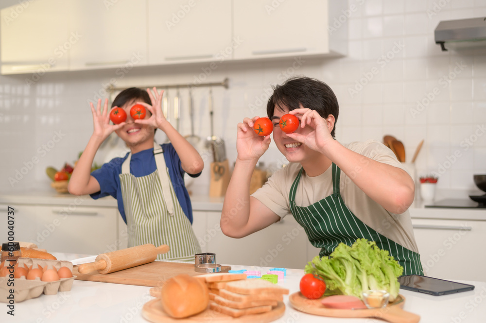 Happy smiling Young Asian father and son holding tomato , enjoy cooking in kitchen at home Happy smiling Young Asian father and son holding tomato , enjoy cooking in kitchen at home