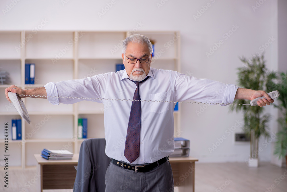 Old male employee doing sport exercises during break Old male employee doing sport exercises during break