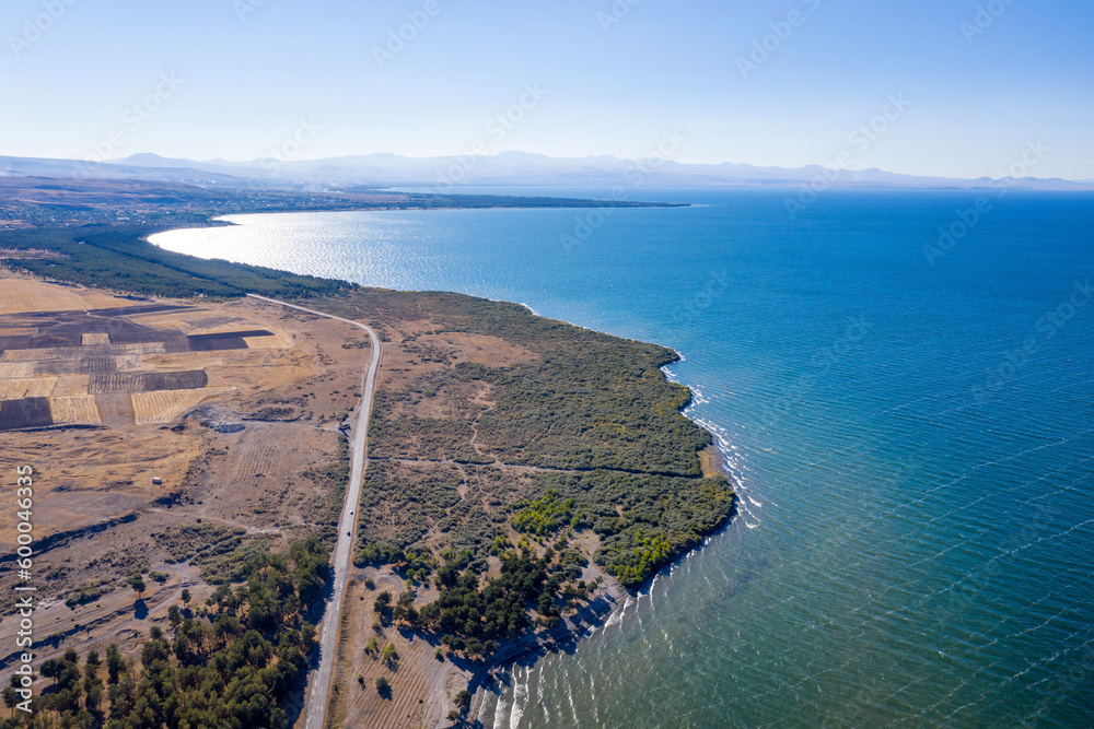 Aerial view of the southern shore of Sevan lake and M11 highway on sunny summer day. Gegharkunik Province, Armenia.