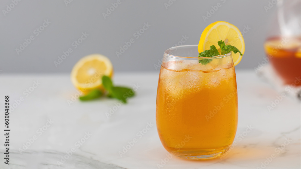 Fototapeta premium A glass with a summer cooling drink. Iced tea with lemon and mint.