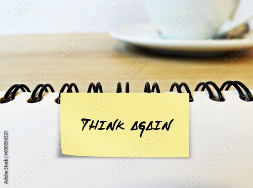 Blur coffee cup and handwritten text stick note on notebook THINK AGAIN, means to think twice before making decision, rethink to lead to excellence at work and wisdom of life