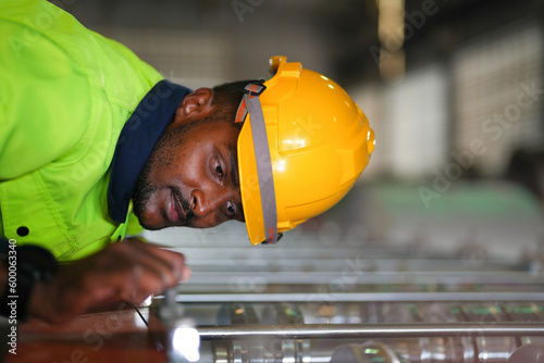 Factory engineer African man checking and reparing mahine at heavy factory.Worker works at heavy machine at industry factory. with machinery equipment plant technology. photo