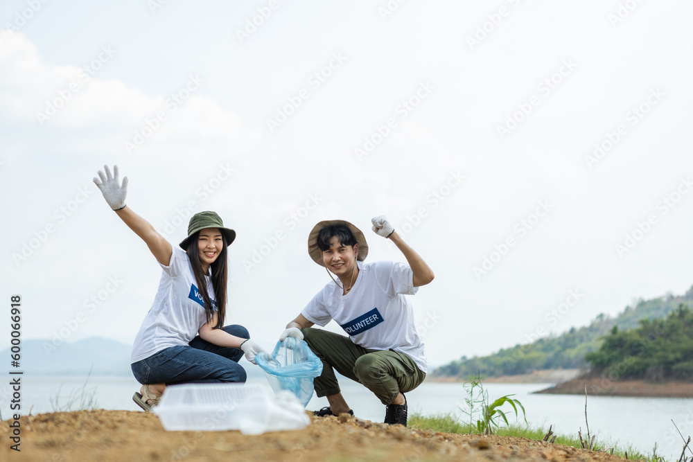 Happy cheerful asian male and female volunteers show hand and collecting garbage, saving world reducing global warming, Volunteers clean plastic bag waste in natural attractions. Happy cheerful asian male and female volunteers show hand and collecting garbage, saving world reducing global warming, Volunteers clean plastic bag waste in natural attractions.