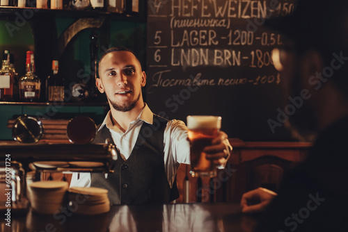 Foto bartender serves a glass of light draft beer to a male guest at bar