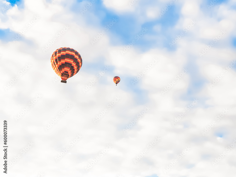 Fototapeta premium Flying in sky many bright colored beautiful balloons into air in Cappadocia in mountains early at sunrise, dawn. Filling balloon with hot air from burner, big basket. Tourists excursion, cloud flight