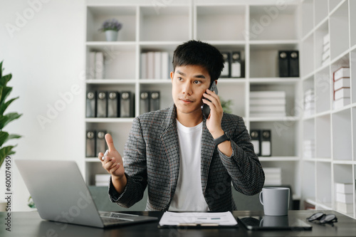 Asian business man executive manager looking at laptop watching online webinar training or having virtual meeting video conference doing market research working in modern office.