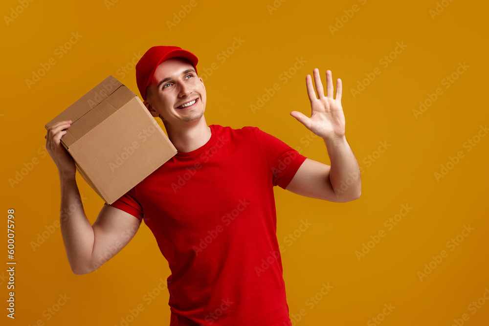 Delivery man employee in red cap, t-shirt holding cardboard box Delivery man employee in red cap, t-shirt holding cardboard box