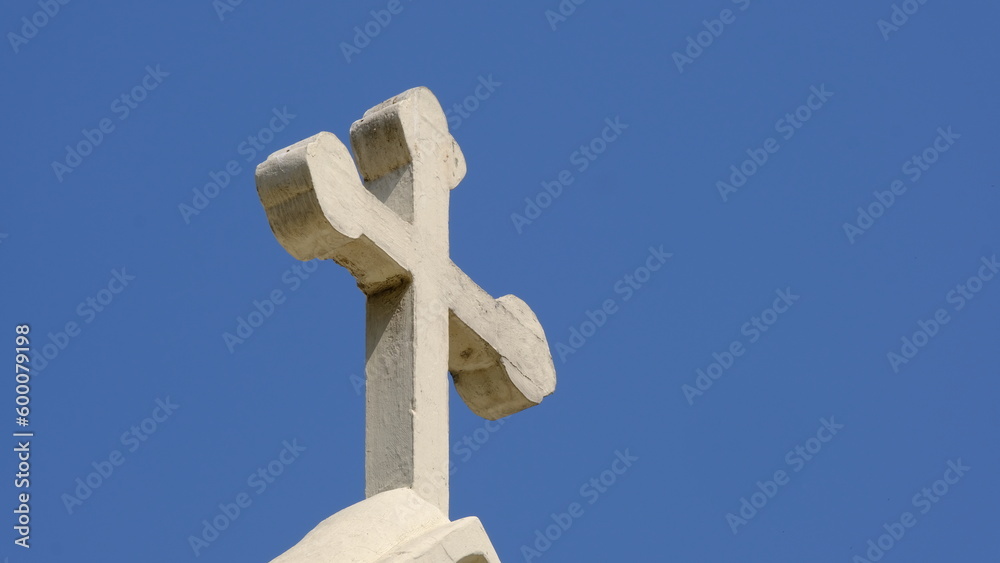 White Christian cross soars isolated into blue sky