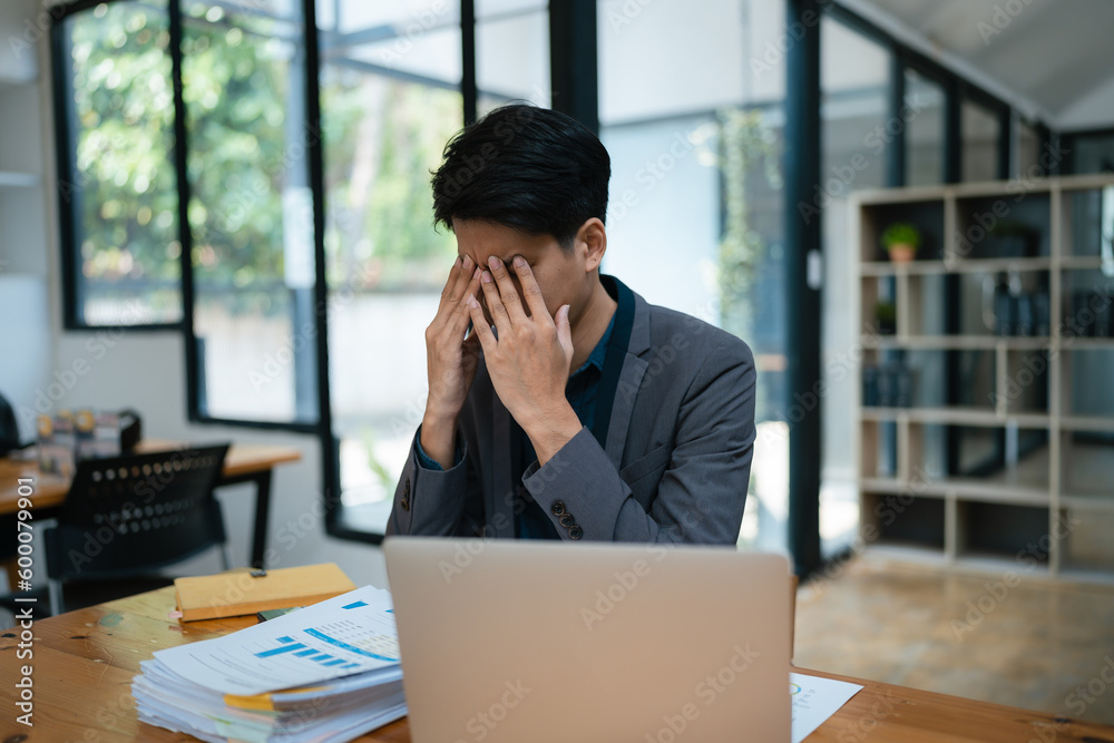 Portrait of business owner, man using computer and financial statements Anxious expression on expanding the market to increase the ability to invest in business. Portrait of business owner, man using computer and financial statements Anxious expression on expanding the market to increase the ability to invest in business.