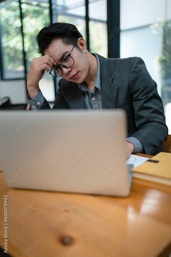 Portrait of business owner, man using computer and financial statements Anxious expression on expanding the market to increase the ability to invest in business. Portrait of business owner, man using computer and financial statements Anxious expression on expanding the market to increase the ability to invest in business.