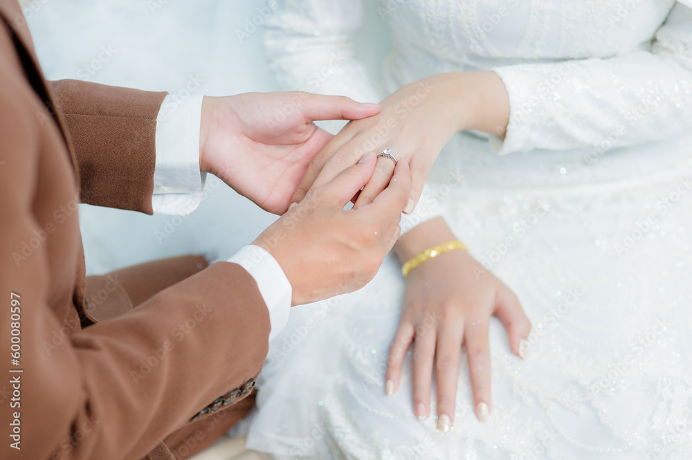 Groom wear wedding rings to left finger of bride, Muslim wedding, Wedding Poster, Close up hand. Groom wear wedding rings to left finger of bride, Muslim wedding, Wedding Poster, Close up hand.