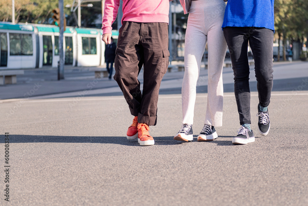 legs of three unrecognizable friends, one man and two women, walking on a sunny day, concept of friendship and urban lifestyle legs of three unrecognizable friends, one man and two women, walking on a sunny day, concept of friendship and urban lifestyle