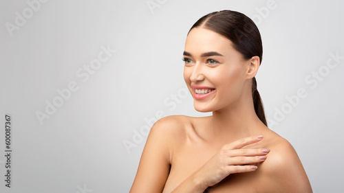 Young Lady Posing Touching Shoulder Skin Looking Aside, Gray Background