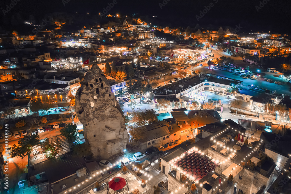 Fototapeta premium Aerial view of illuminated streets, fairy chimneys and cave hotels at Goreme village, Nevsehir province, Cappadocia, Turkiye