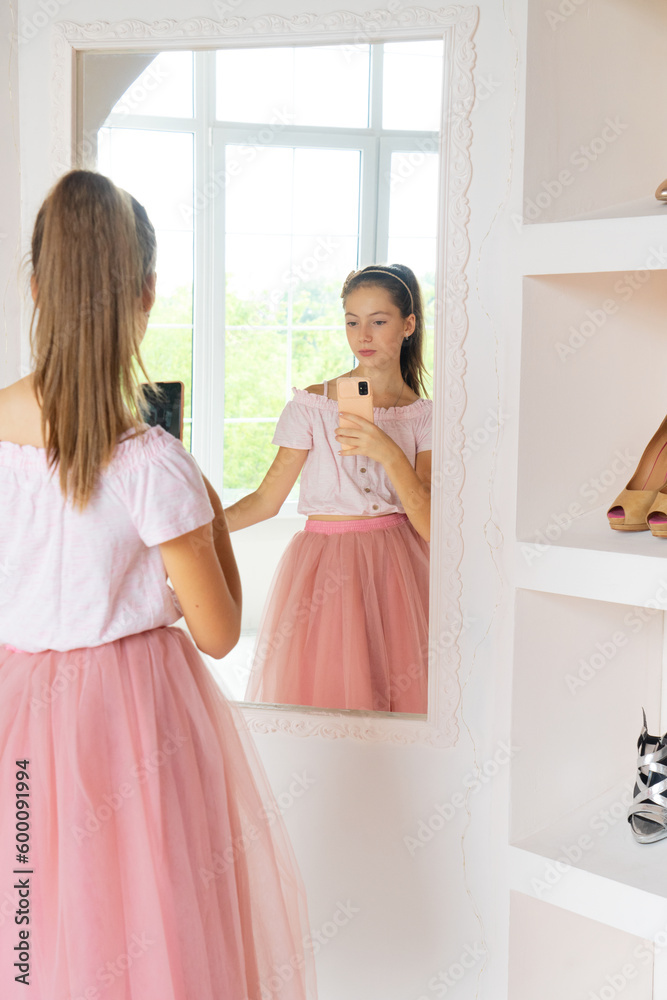 Naklejka premium Teen girl in tutu-skirt and high-heeled shoes making selfie on smartphone