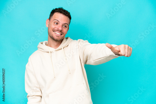 Young caucasian handsome man isolated on blue background giving a thumbs up gesture © luismolinero