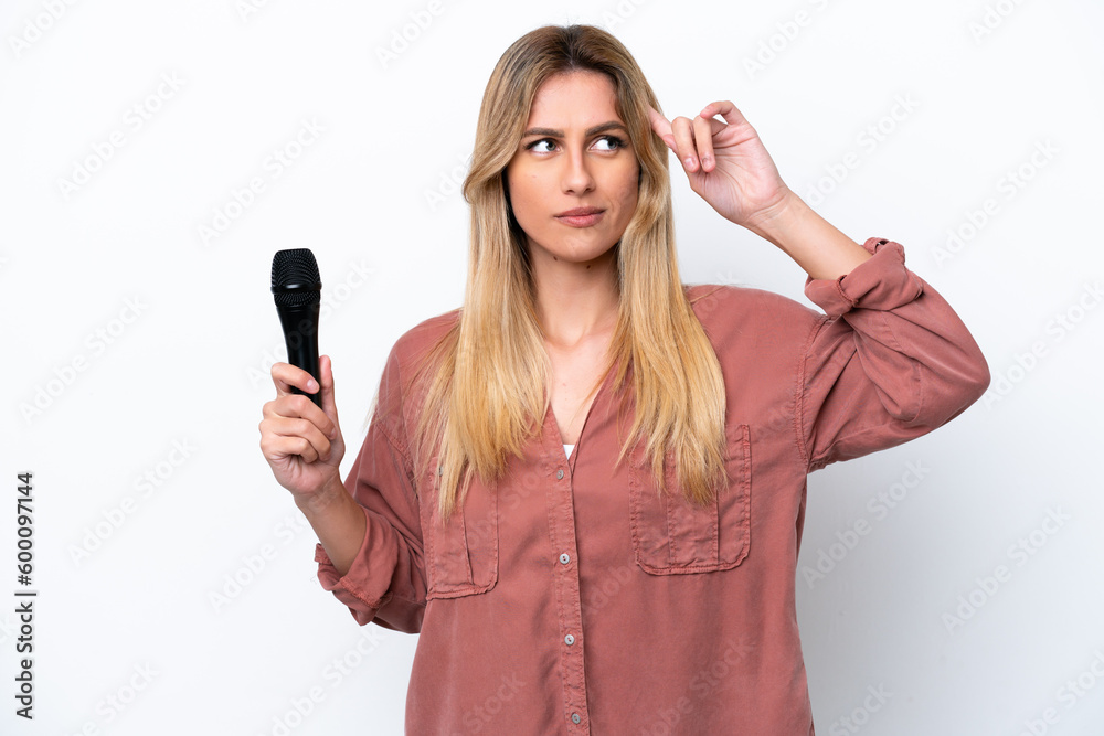 Singer Uruguayan woman picking up a microphone isolated on white background having doubts and thinking Singer Uruguayan woman picking up a microphone isolated on white background having doubts and thinking