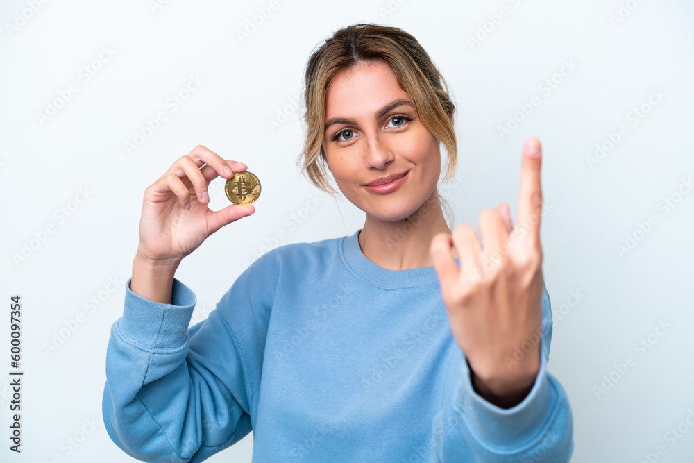 Young Uruguayan woman holding a Bitcoin isolated on white background doing coming gesture Young Uruguayan woman holding a Bitcoin isolated on white background doing coming gesture
