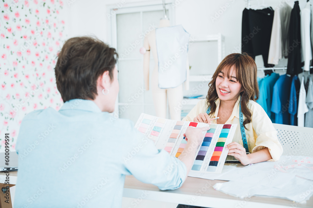 Young designer is suggesting the right color scheme to a customer in a workroom full of clothes.