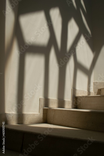 Beautiful spiral staircase made of off white marble and a beautiful artistic diamond shaped shadow on the wall on the side of stairs or in it's background. © Siyyam