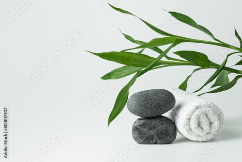 Light gray background with stones, towel and bamboo.