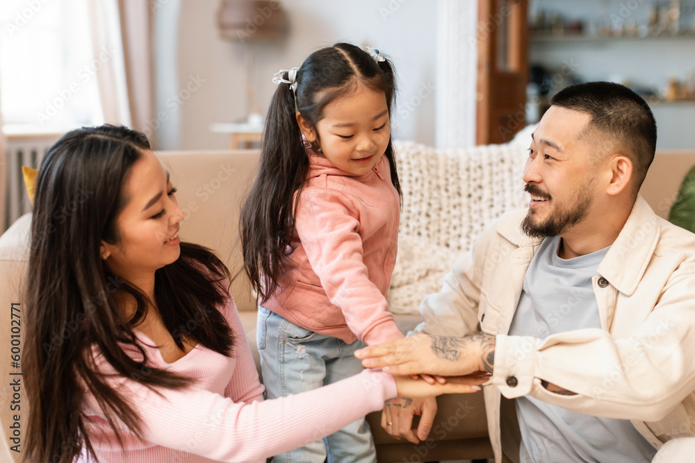 Joyful Korean Family Stacking Hands In Togetherness Symbol Playing Indoors Joyful Korean Family Stacking Hands In Togetherness Symbol Playing Indoors